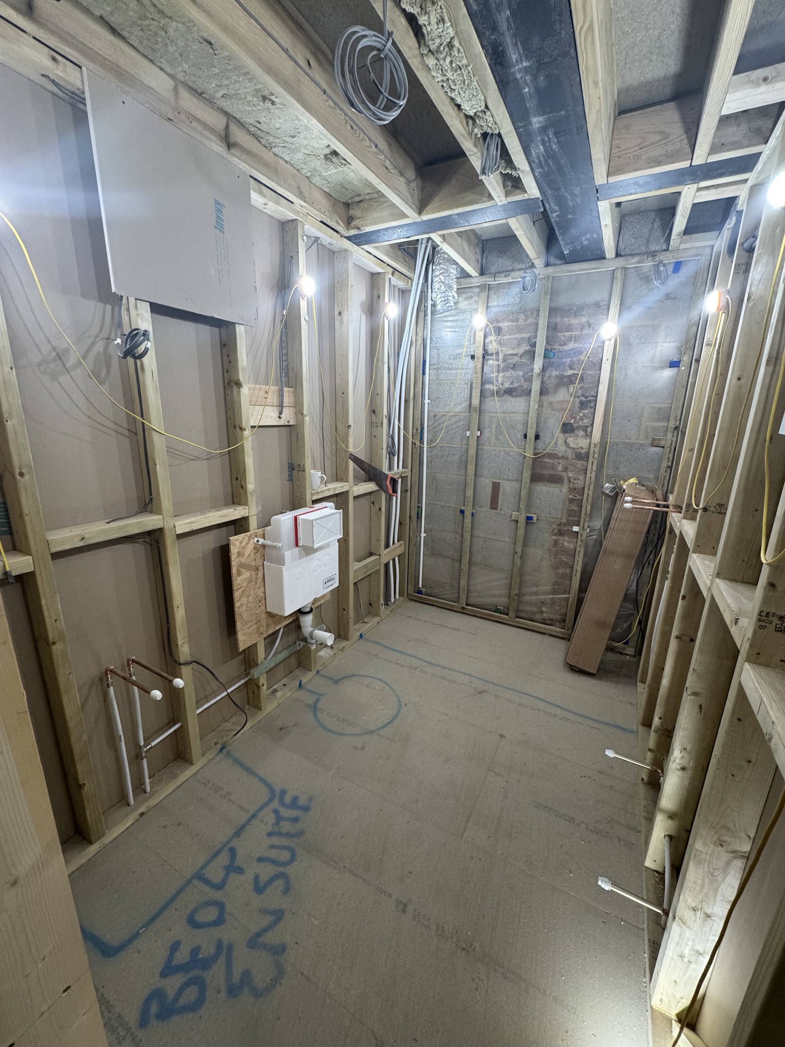 An en-suite at first-fix stage — concealed cistern, hot and cold supplies and waste run in before plastering.